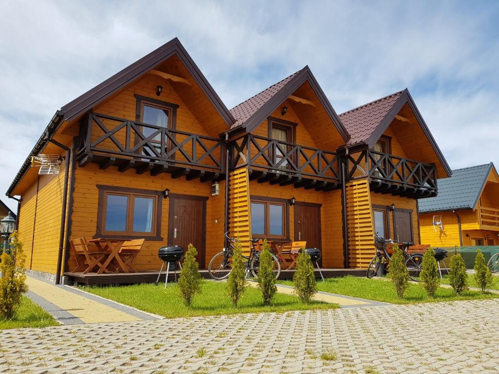 ein großes Holzhaus mit einer Veranda in der Unterkunft domki letniskowe "U EWKI" in Sarbinowo
