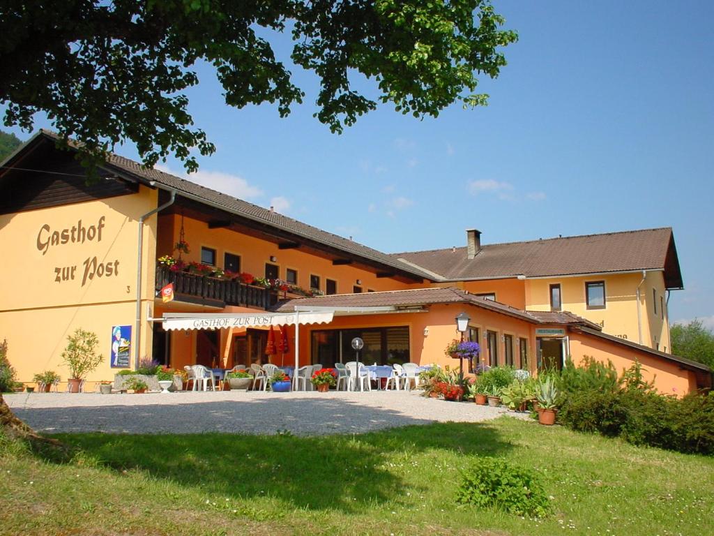 ein Gebäude mit Tischen und Stühlen davor in der Unterkunft Gasthof Hotel Zur Post in Ferlach