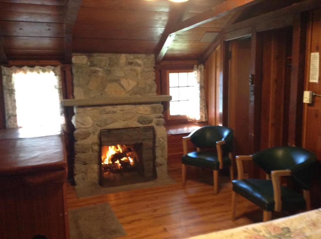 a living room with a stone fireplace and two chairs at Addison's Bungalows in Brisco