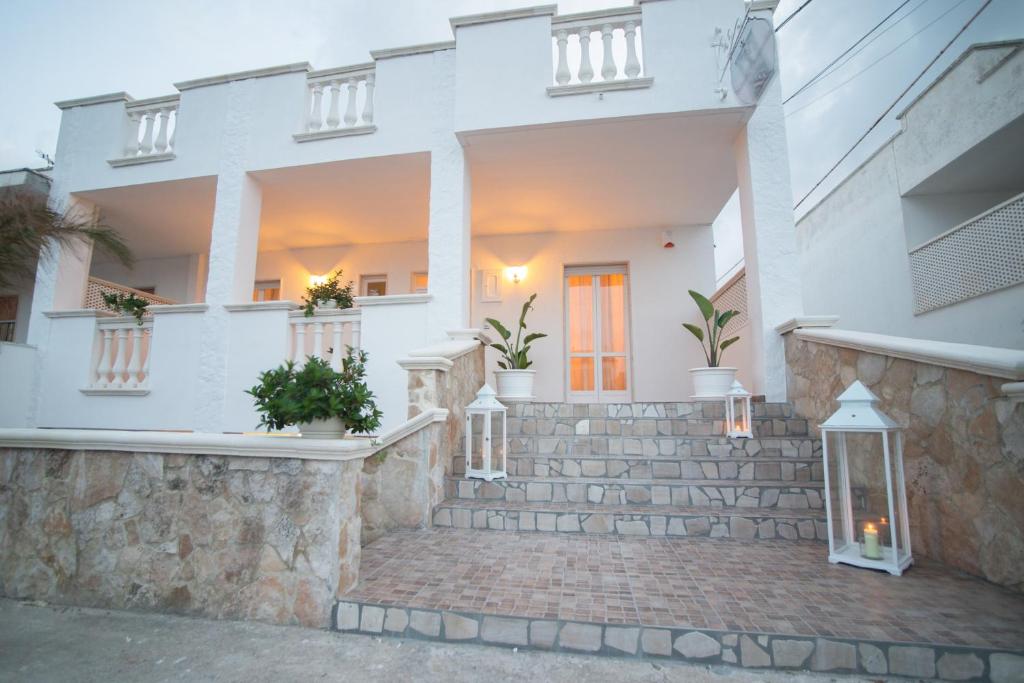 マリーナ・ディ・マンカヴェルサにあるCORTE DELL'IMMACOLATA AL MAREの階段と鉢植えの白い家