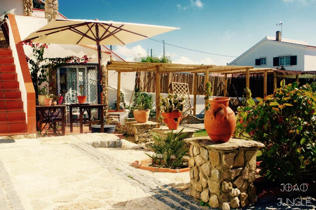 a patio with an umbrella and vases on a stump at João Jungle in Açafora