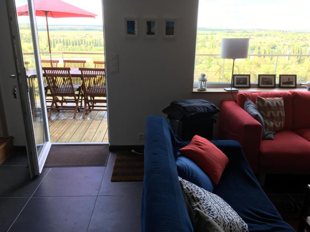 a living room with a couch and a view of a deck at VUE SEINE Chambre Panorama in La Bouille