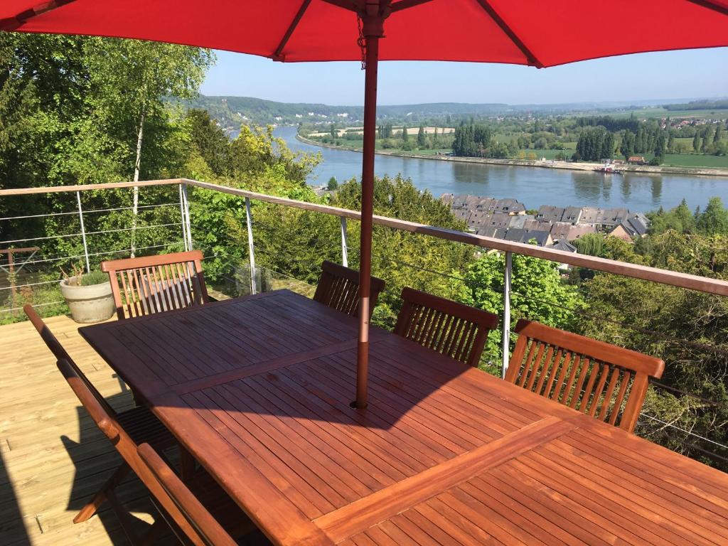 a wooden table with an umbrella on a deck at VUE SEINE Chambre Panorama in La Bouille