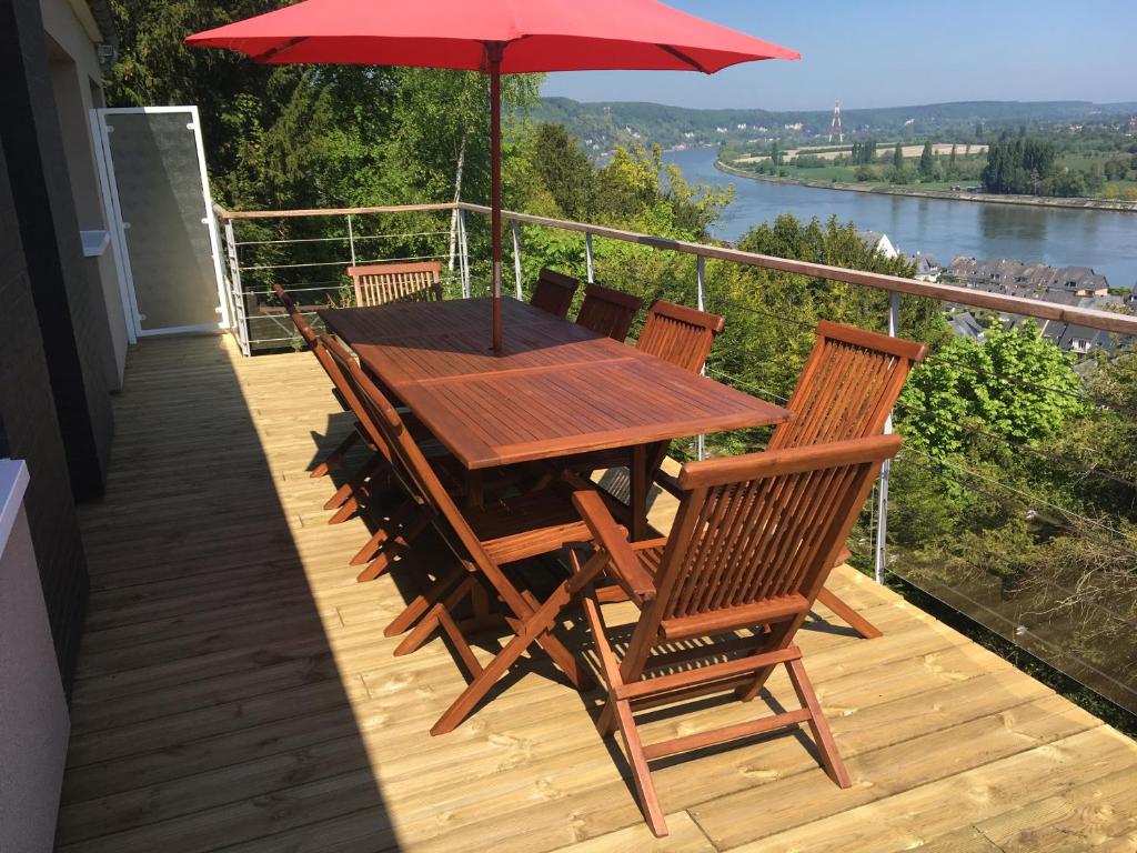 a wooden table and chairs on a deck with an umbrella at VUE SEINE Chambre Panorama in La Bouille