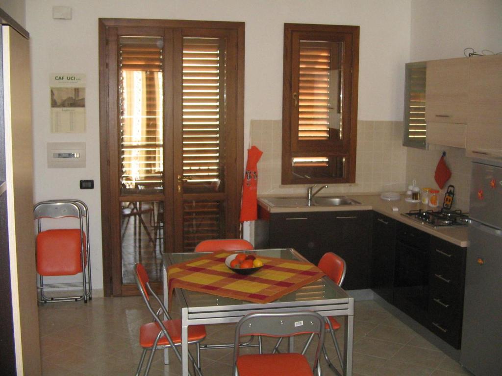 a kitchen with a table and chairs and a kitchen with a sink at Annalisa Apartments 250 dal mare in San Vito lo Capo