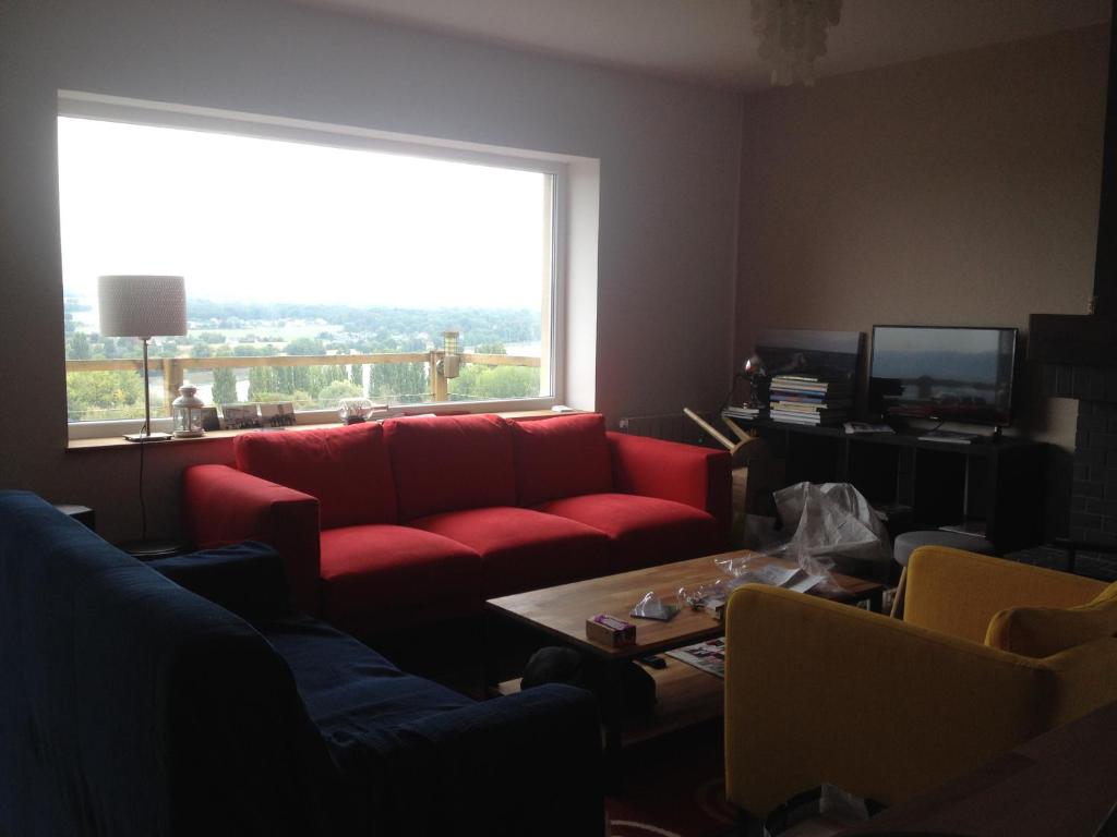 a living room with a red couch and a large window at VUE SEINE Chambre Panorama in La Bouille