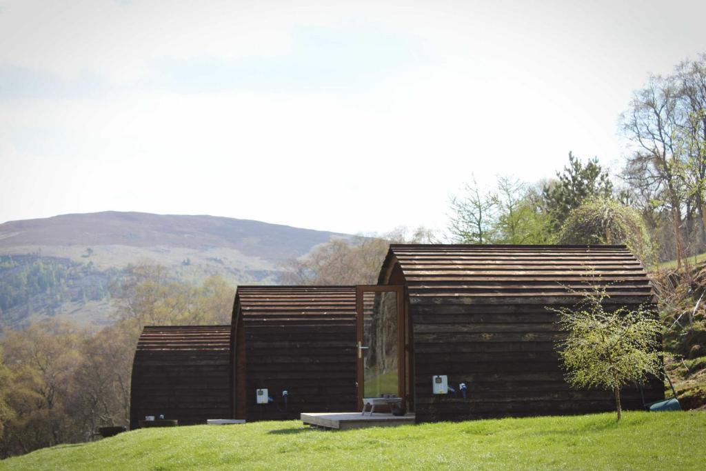 ein kleines Holzgebäude auf einem grasbewachsenen Hügel in der Unterkunft Howe of Torbeg in Ballater