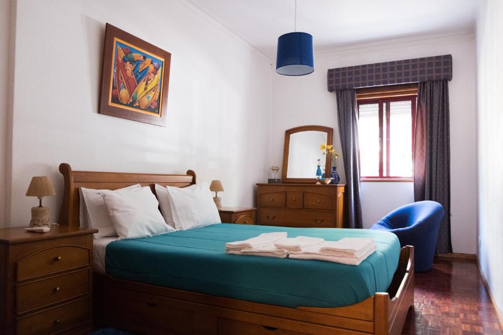 een slaapkamer met een bed met een blauwe stoel en een spiegel bij Apartamento Tavira in Tavira