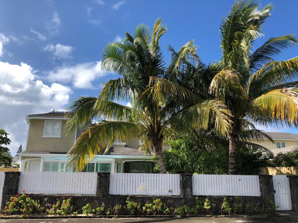 einen weißen Zaun vor einem Haus mit Palmen in der Unterkunft Villa De Alisha in Blue Bay