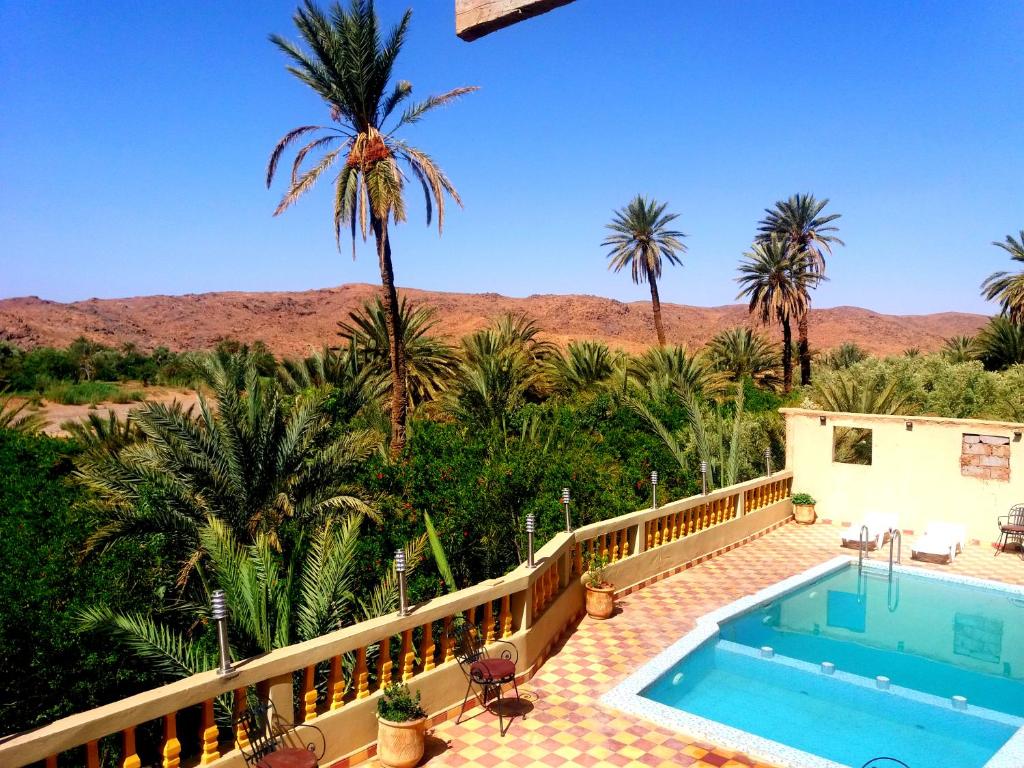 a resort with a swimming pool and palm trees at Kasbah Elmehdaoui in Skoura