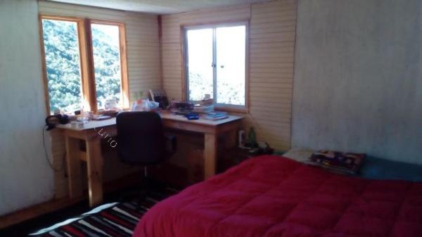1 dormitorio con escritorio y 1 cama con manta roja en Cabaña en Canelo Cajón del Maipo, en San José de Maipo