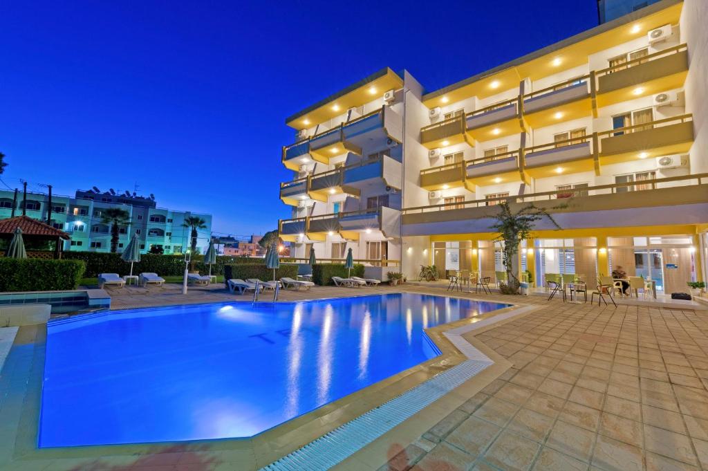 a swimming pool in front of a building at night at Trianta Hotel Apartments in Ialysos