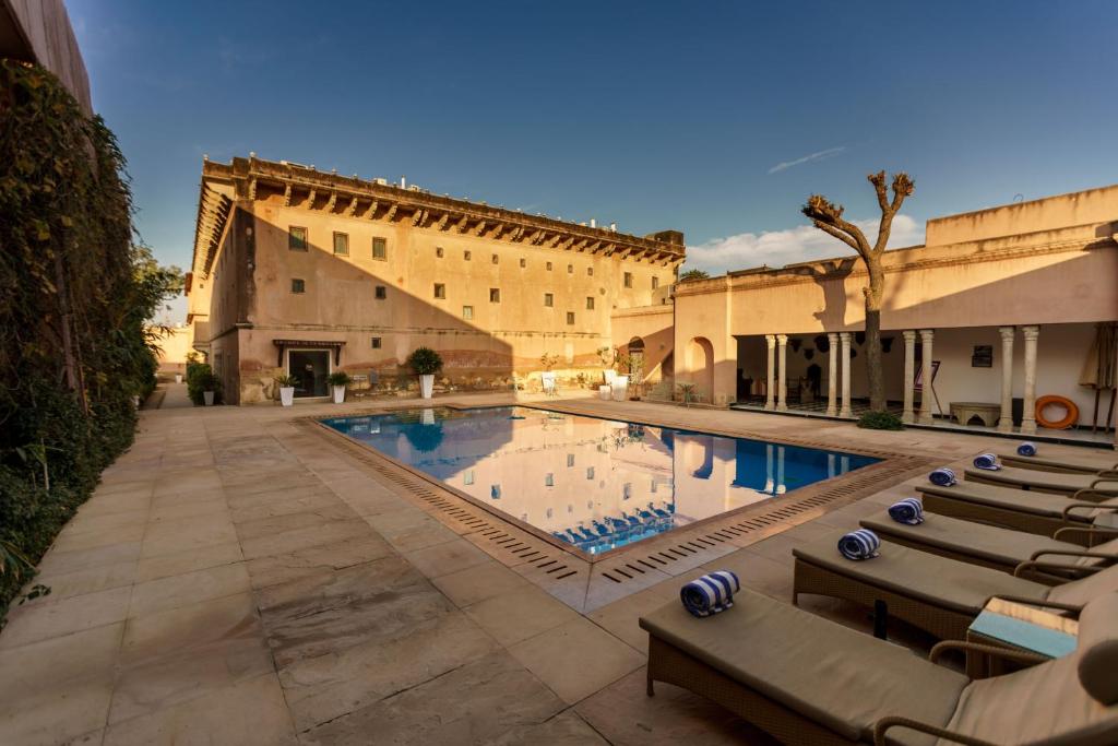 una piscina in un cortile con sedie e un edificio di Vivaana Culture Hotel a Mandawa