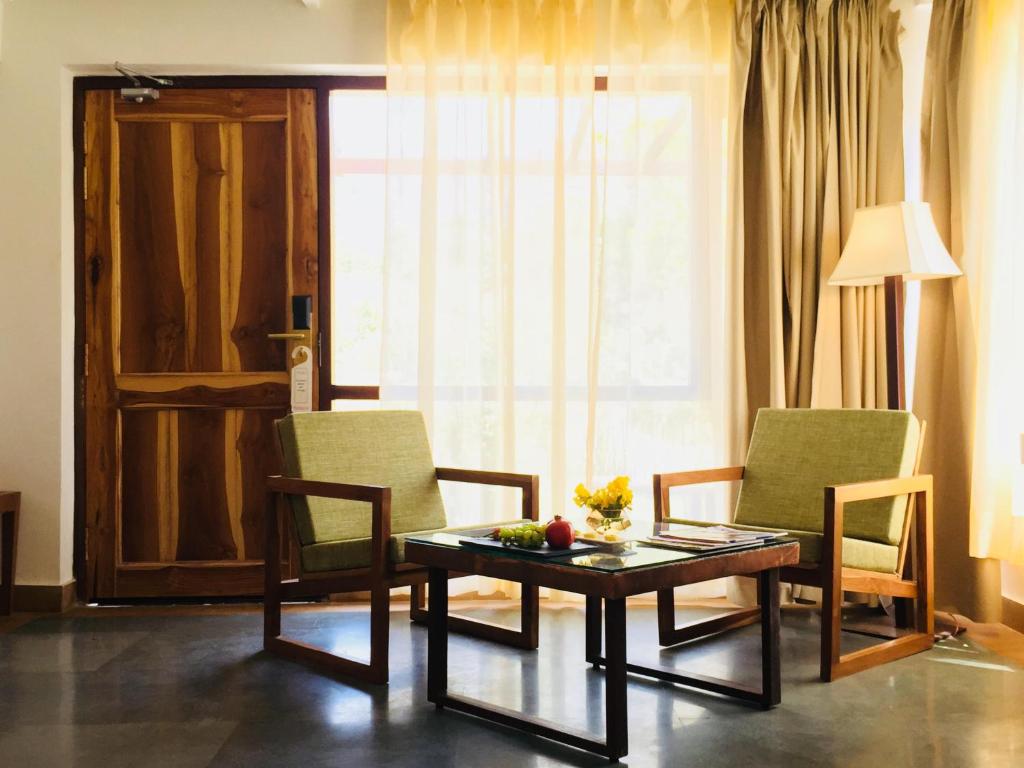 a living room with a table and chairs and a window at Saraca Resort & Spa Corbett in Garjia