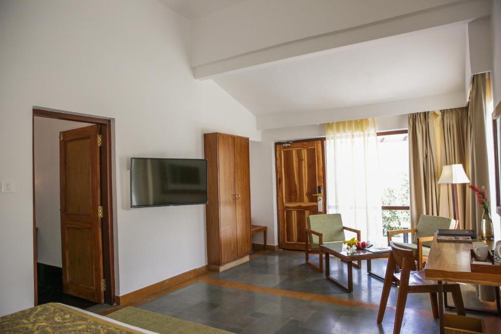 a living room with a television and a table and chairs at Saraca Resort & Spa Corbett in Garjia