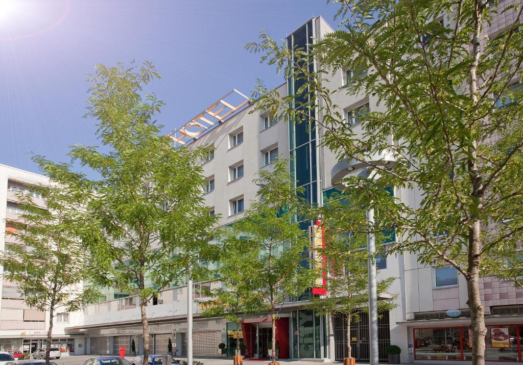 een wit gebouw met bomen ervoor bij Hotel City in Villach