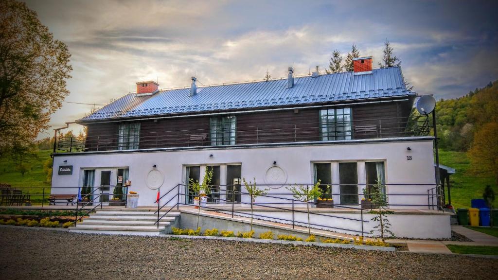 a large white house with a blue roof at Leonówka Bieszczady in Cisna