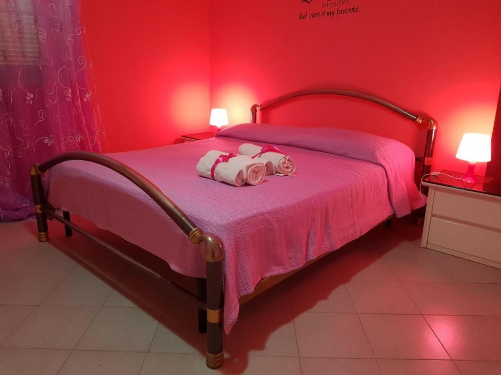 um quarto rosa com uma cama com um bicho de peluche em Casa Loredana em Scauri