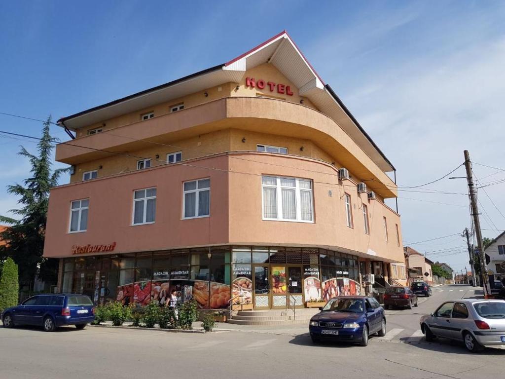 un gran edificio con coches estacionados frente a él en Hotel Floare de Colt, en Teiuş