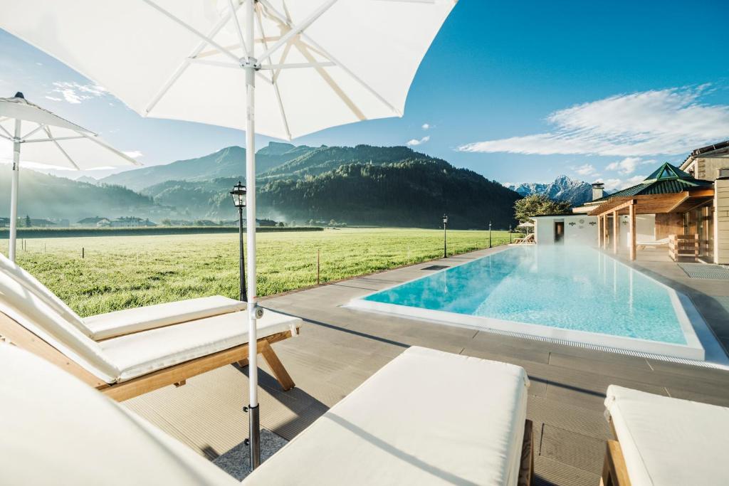 a swimming pool with an umbrella and a chair at Theresa Wellness-Genießer-Hotel in Zell am Ziller