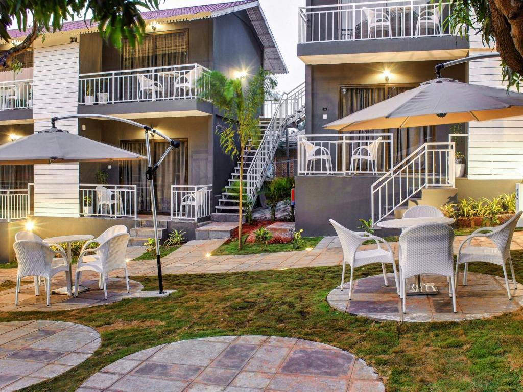 a patio with chairs and umbrellas in front of a building at Oceans 7 Ashwem in Mandrem