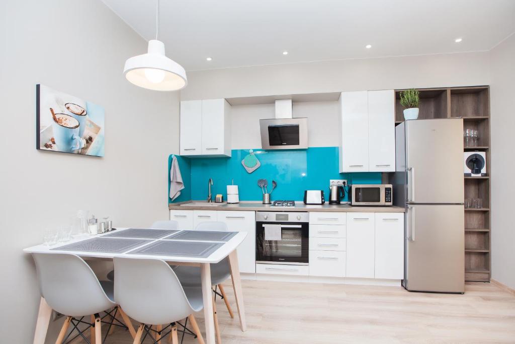 カリーニングラードにあるCloud 9 apartmentsの白いキャビネット、テーブルと椅子付きのキッチンが備わります。