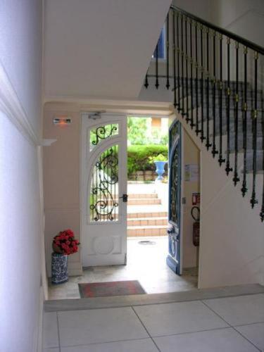 a hallway with a white door and stairs with a vase of flowers at Hotel Le Havre Bleu in Beaulieu-sur-Mer