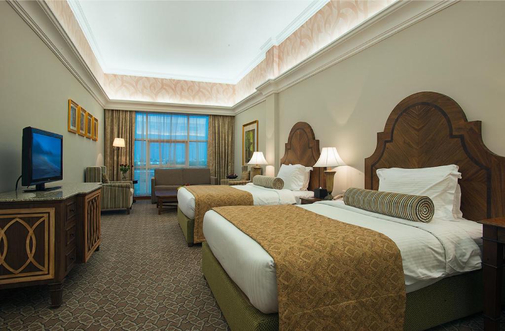 a hotel room with two beds and a flat screen tv at Ayla Hotel in Al Ain