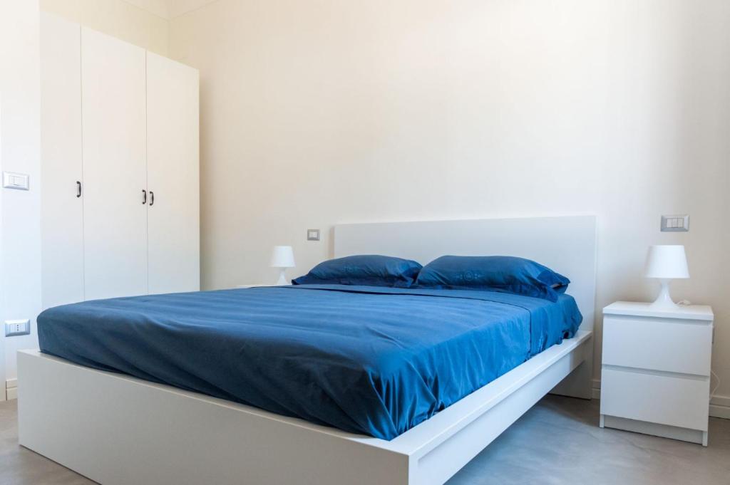 ein weißes Schlafzimmer mit einem großen Bett mit blauer Bettwäsche in der Unterkunft Appartamenti Casalvelino in Casal Velino