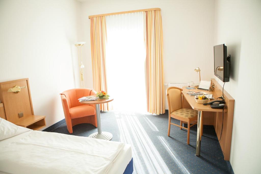 Cette chambre comprend un lit, un bureau et une table. dans l'établissement Hotel Seltenbacher Hof, à Tuttlingen