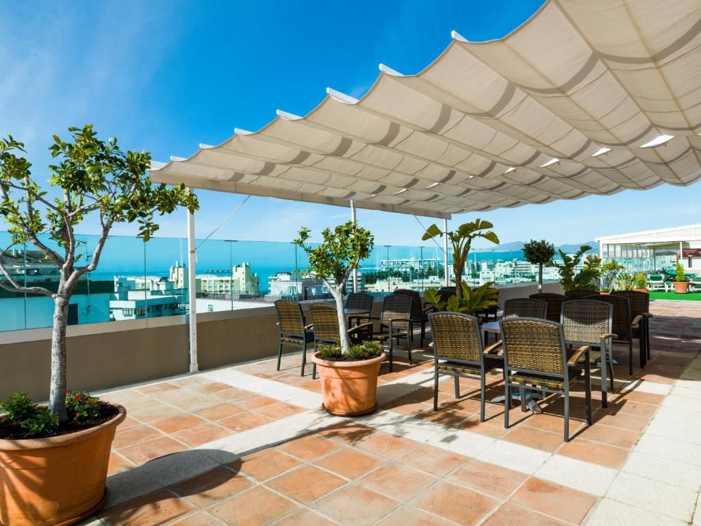 a patio area with chairs, tables and umbrellas at Hotel Monarque El Rodeo in Marbella