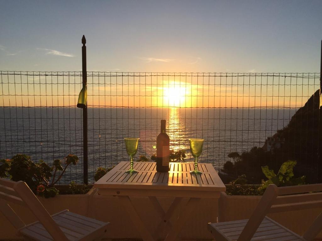 a bottle of wine and glasses on a table with the sunset at Villa Pecunia in Riomaggiore