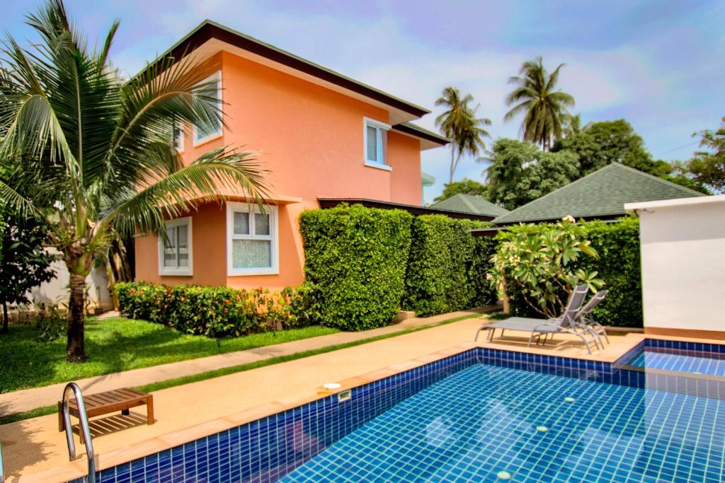 a villa with a swimming pool in front of a house at Blue Wave Samui in Bophut