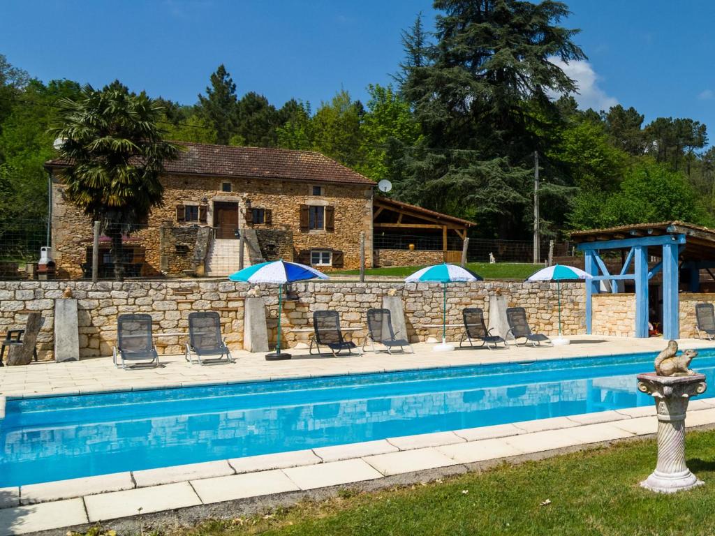 una piscina con sedie e ombrelloni di fronte a una casa di Beautiful holiday home with private pool a Saint-Cernin-de-lʼHerm