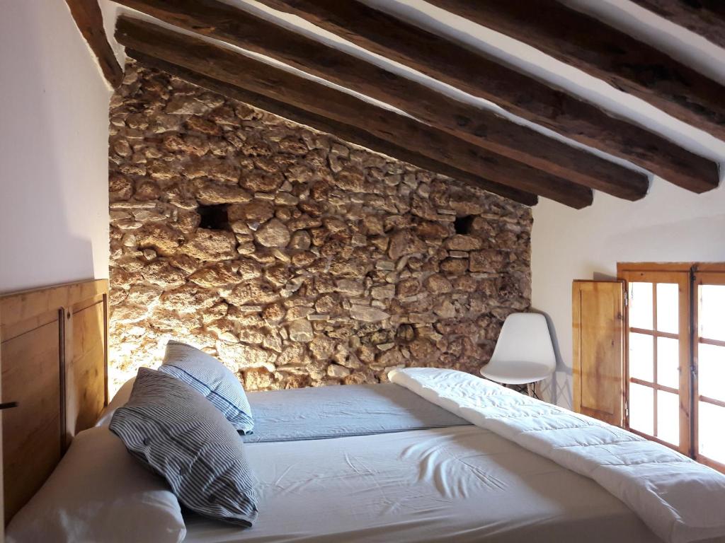 Cama en habitación con pared de piedra en Can Jaume Porxo, en Pratdip