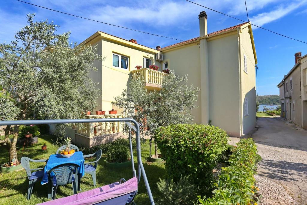 een huis met een tafel en stoelen in een tuin bij Seaview apartment Aida in Posedarje