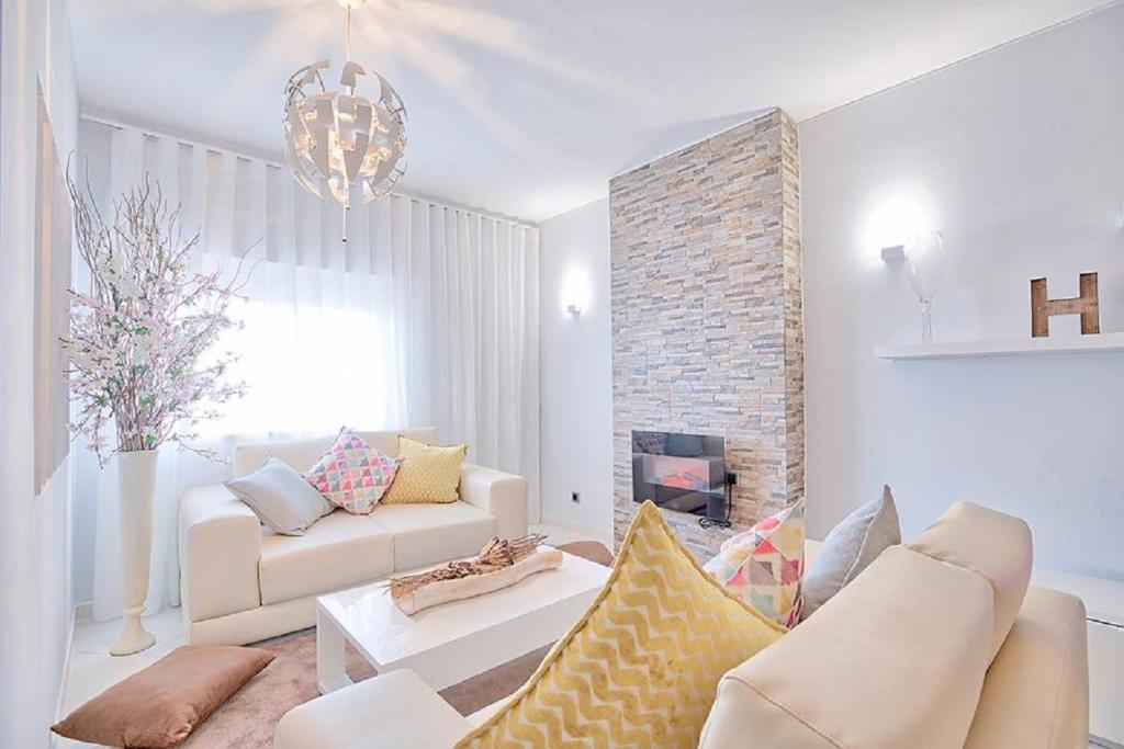 uma sala de estar com mobiliário branco e uma parede de tijolos em APARTAMENTO MICÁ em Albufeira