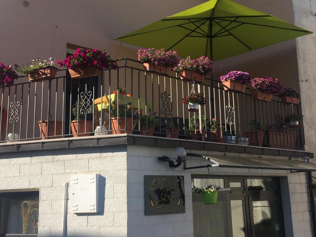 a balcony with potted plants and a green umbrella at La Casa Dei Fiori in Montecilfone