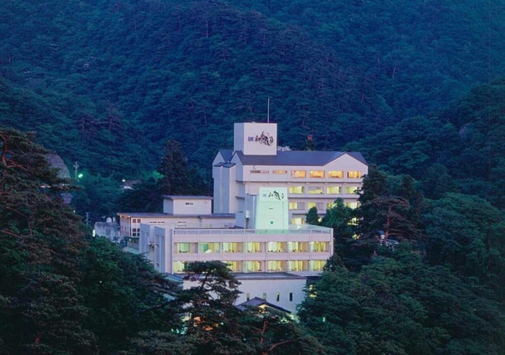 un grand bâtiment sur le côté d'une montagne dans l'établissement Higashiyama Park Hotel Shinfugetsu, à Aizuwakamatsu