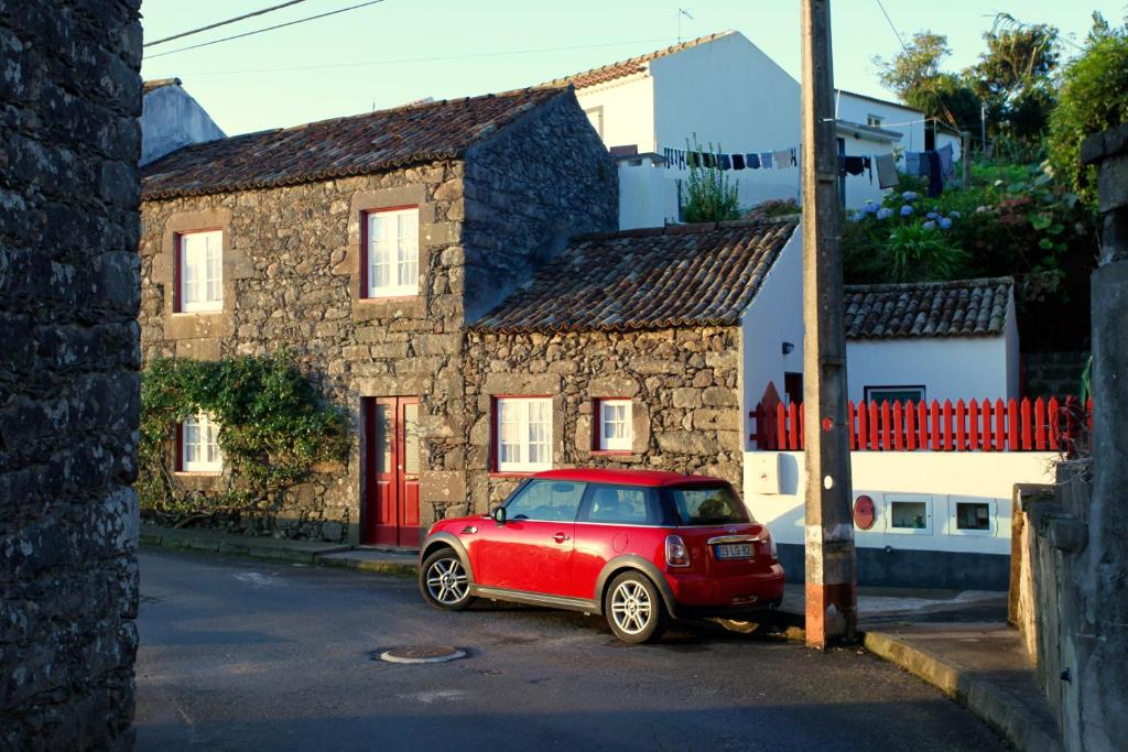 une voiture rouge garée devant une maison en pierre dans l'établissement Casa da Roseira, à Nordeste