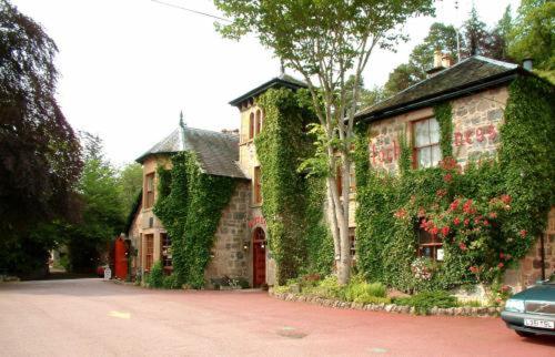 a building covered in ivy next to a street at Loch Ness Lodge Hotel in Drumnadrochit