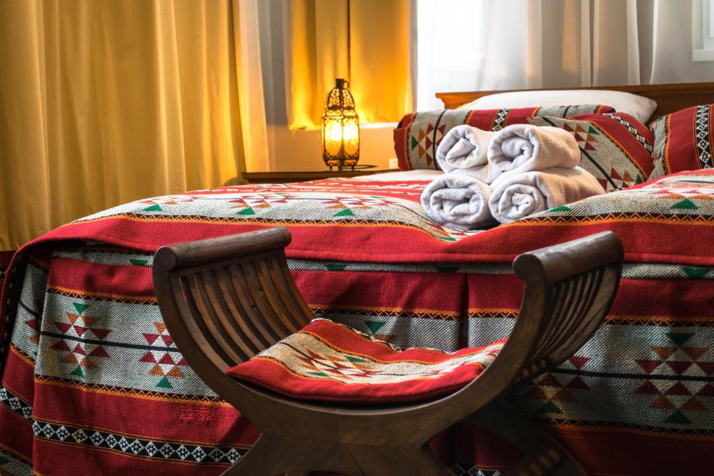 um quarto com uma cama com um cobertor e uma cadeira em Petra Hotel em Nyíregyháza