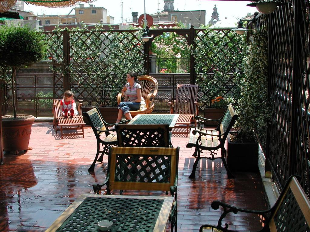 un homme et un enfant assis à une table sur un patio dans l'établissement Hotel Adriatic, à Rome