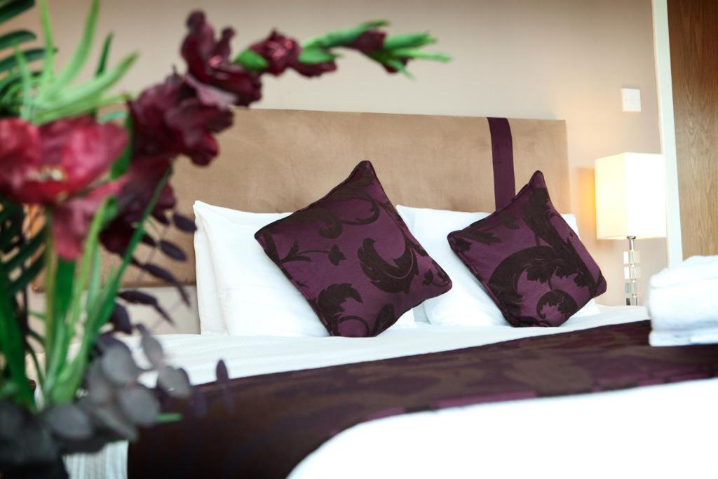グラスゴーにあるThe Spires Serviced Apartments Glasgowのベッドルーム1室(紫と白の枕が備わるベッド1台付)