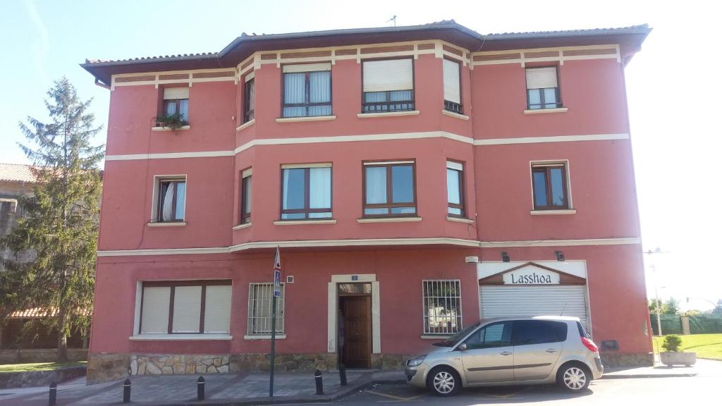 a red building with a car parked in front of it at Apartamento Loiu in Loiu