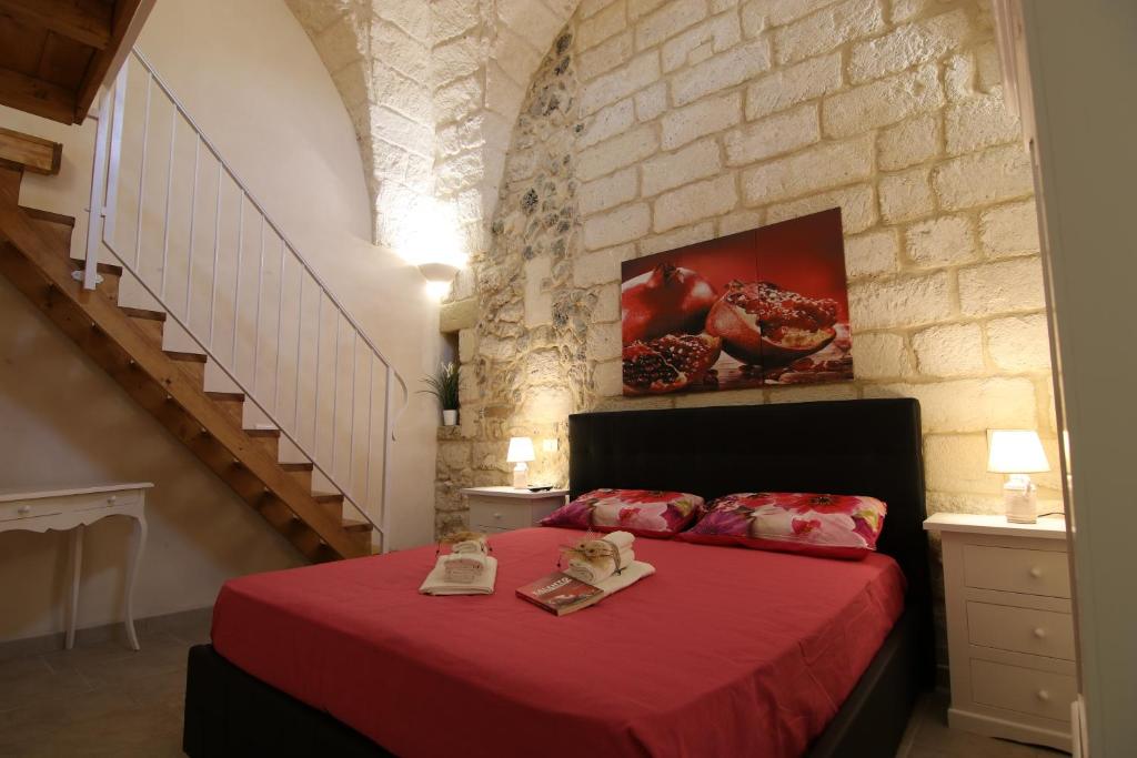 una camera con letto rosso e parete in mattoni di Corte Manzoni a Melendugno