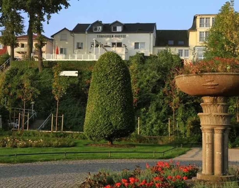un vase dans un jardin avec une maison en arrière-plan dans l'établissement Pension Radke, à Heringsdorf