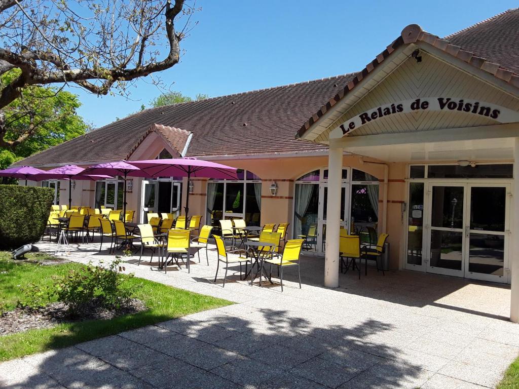 un restaurante con mesas, sillas y sombrillas púrpuras en Le Relais de Voisins en Voisins-le-Bretonneux