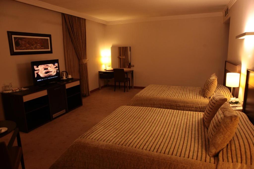 アダナにあるAkkoc Boutique Hotelのベッド2台、薄型テレビが備わるホテルルームです。