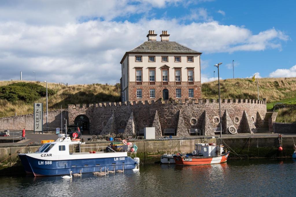 two boats are docked in the water in front of a building at Merchant's House - LARGE two floor apartment!! Sleeps up to 11 people, First floor available separately, sleeping 2 people at a reduced rate!!! in Eyemouth